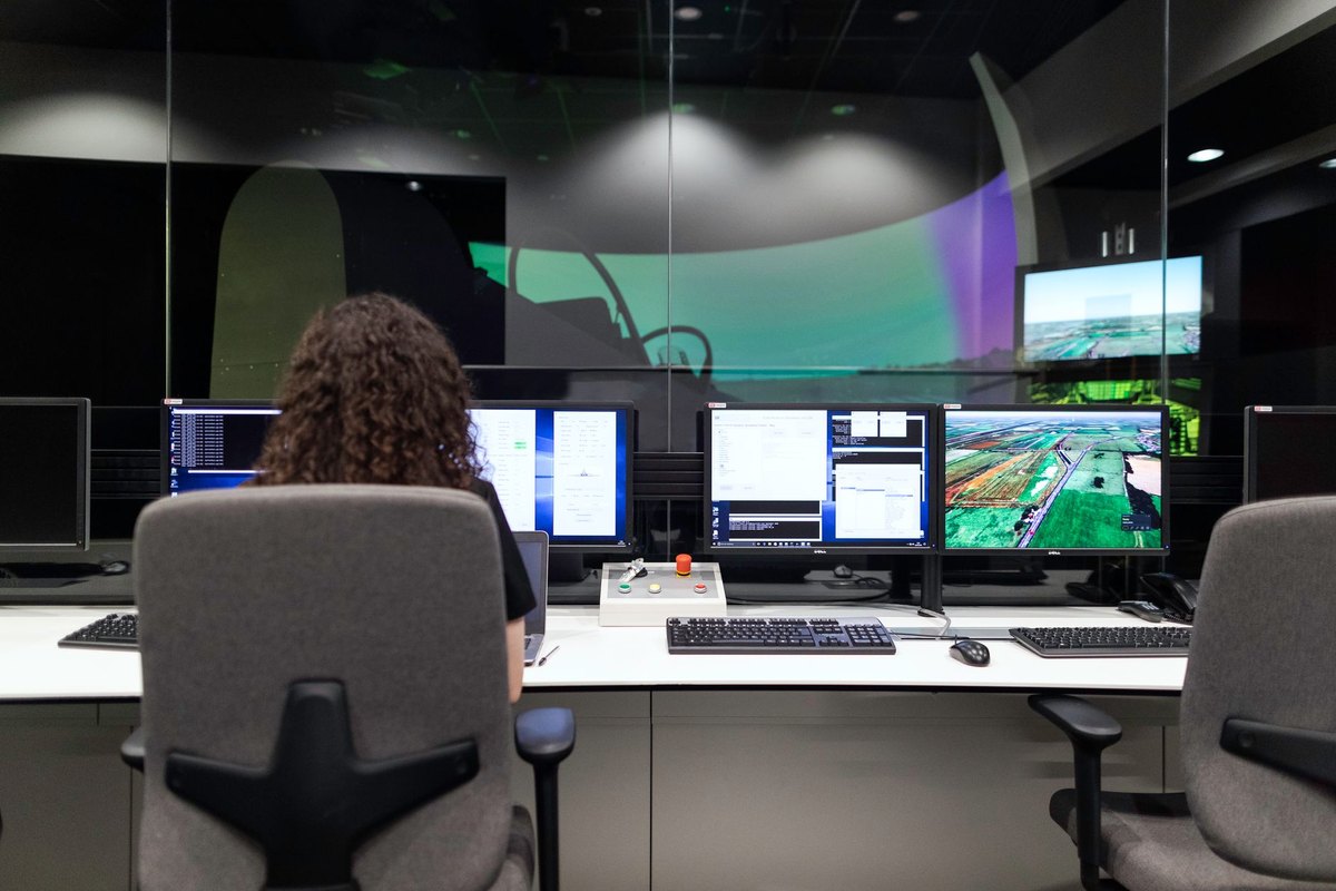 A data engineer analyzing renewable energy system performance on multiple computer monitors in a modern control room.